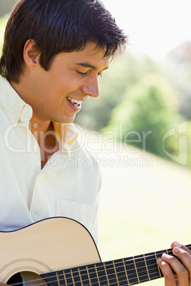 Man smiling as he plays a guitar