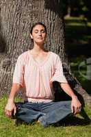 Woman sitting in a yoga pose with her hands placed on her knees