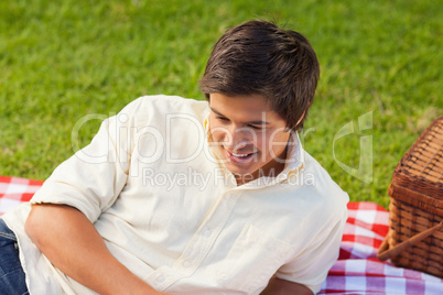 Man smiling as he lie on a picnic blanket