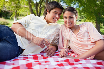 Man looking at his friend while as they lie down on a blanket wh