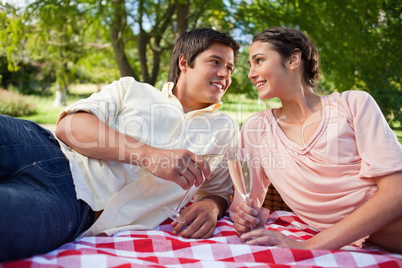 Two friends looking at each other while holding glasses during a