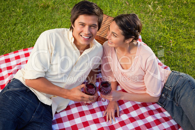 Woman looks at her friend while holding glasses of wine during a