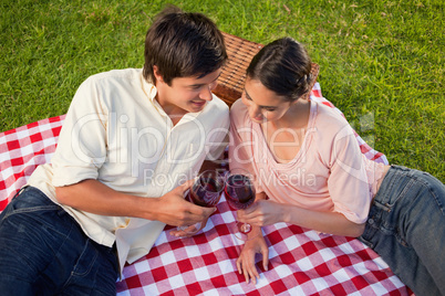 Two friends looking downwards while holding glasses of wine duri