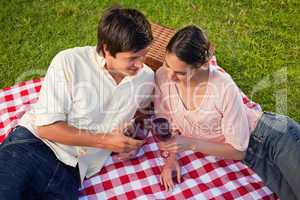 Two friends looking downwards while holding glasses of wine duri