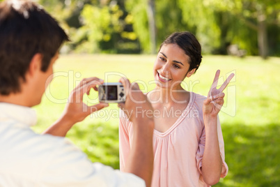 Man takes a photo of his friend giving the peace sign