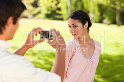 Man takes a photo of his friend while she poses