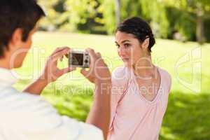 Man takes a photo of his friend while she poses
