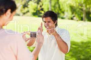 Woman takes a photo of his friend while he poses