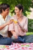 Two friends smiling while touching glasses of juice during a pic