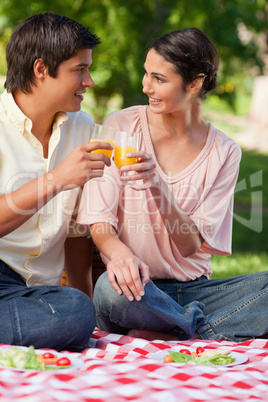 Two friends looking at each other while touching glasses of juic