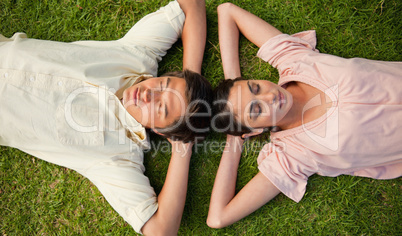 Two friends lying head to head with both hands behind their neck