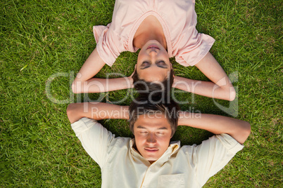 Woman and a man lying head to head with both hands behind their