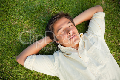 Man lying with his eyes closed and both hands behind his neck