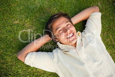 Man smiling as he lies with both hands behind his neck