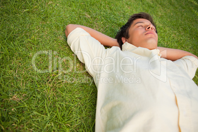 Man lying in grass with his eyes closed and his head resting on