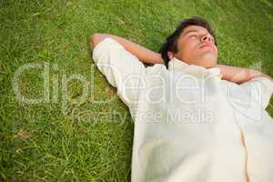 Man lying in grass with his eyes closed and his head resting on