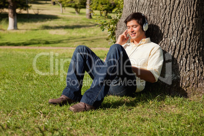 Man smiling while listening to music through headphones while re