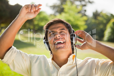 Man raising his arms while using headphones to sing along to mus