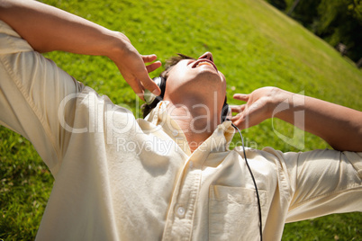 Man using headphones to sing along to music while lying in grass