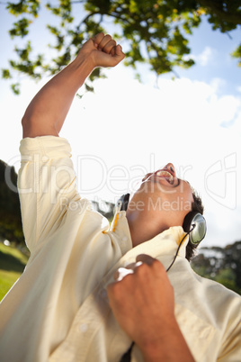 Man raising his arm while using headphones to listen to music in