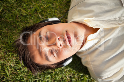 Man closes his eyes while using headphones to listen to music as