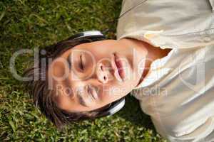 Man closes his eyes while using headphones to listen to music as