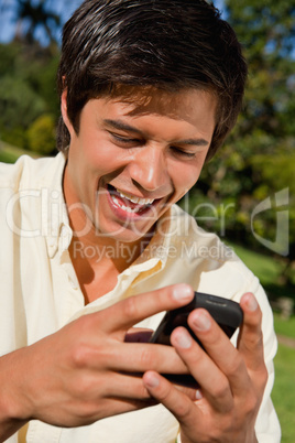 Close-up of a man using a phone while he is sitting down