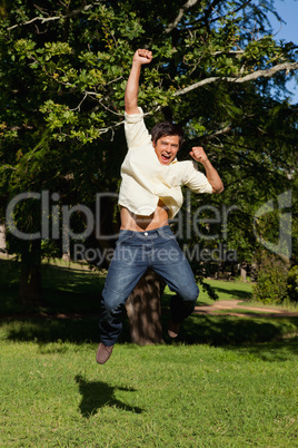 Man laughing as he jumps with his arms raised in celebration