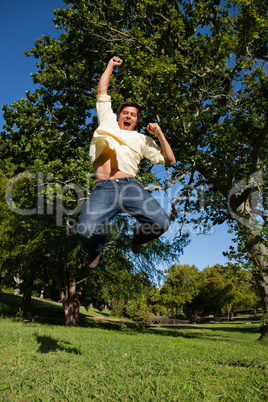 Man looking down to the ground as he jumps with his arms raised