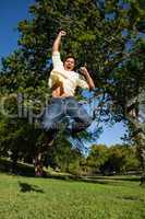 Man looking down to the ground as he jumps with his arms raised