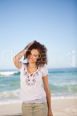 Young woman standing in front of the sea with hand on her head