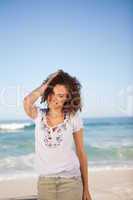 Young woman standing in front of the sea with hand on her head