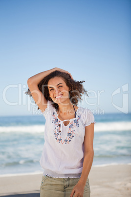 Young smiling woman holding her hair on the beach