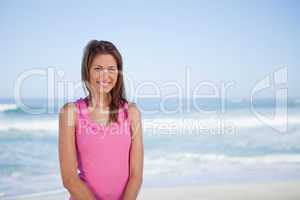 Young smiling woman standing upright in front of the sea