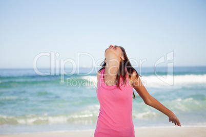 Young relaxed woman standing on the beach while sunbathing