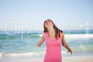 Young smiling woman enjoying the sun while standing on the beach
