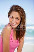 Young smiling woman standing in front of the sea while turning h