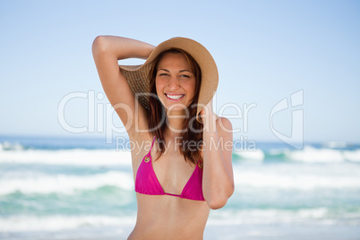 Smiling teenager holding her hat in front of the sea