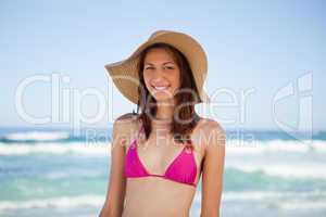 Smiling teenage girl wearing a hat while standing on the beach