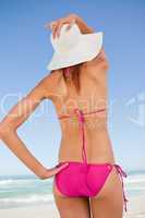 Back view of an attractive teenager in beachwear holding her str