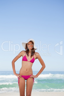 Smiling young attractive woman placing her hands on hips in fron