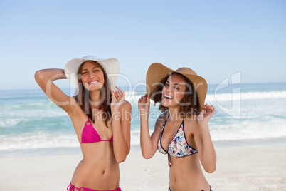 Happy young women standing on the beach side by side