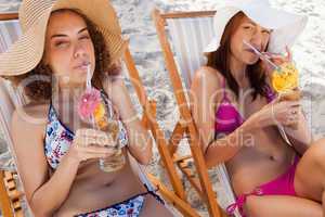 Young women sipping their exotic cocktails on the beach