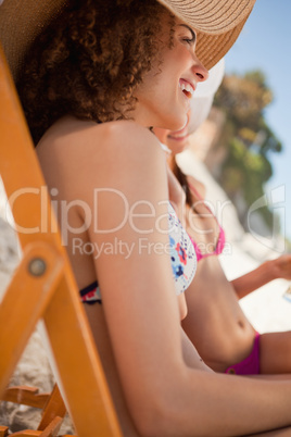 Side view of young attractive women sitting on deck chairs