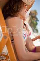 Side view of young attractive women sitting on deck chairs