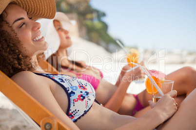 Smiling young woman sitting in a deck chair while holding her co