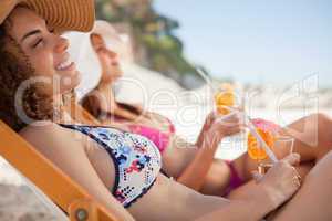 Smiling young woman sitting in a deck chair while holding her co