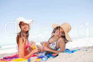 Young smiling women lying on beach towels while looking at the c