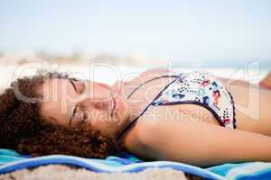 Side view of an attractive woman napping on the beach while turn