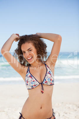 Smiling young woman raising her arms above the head in front of
